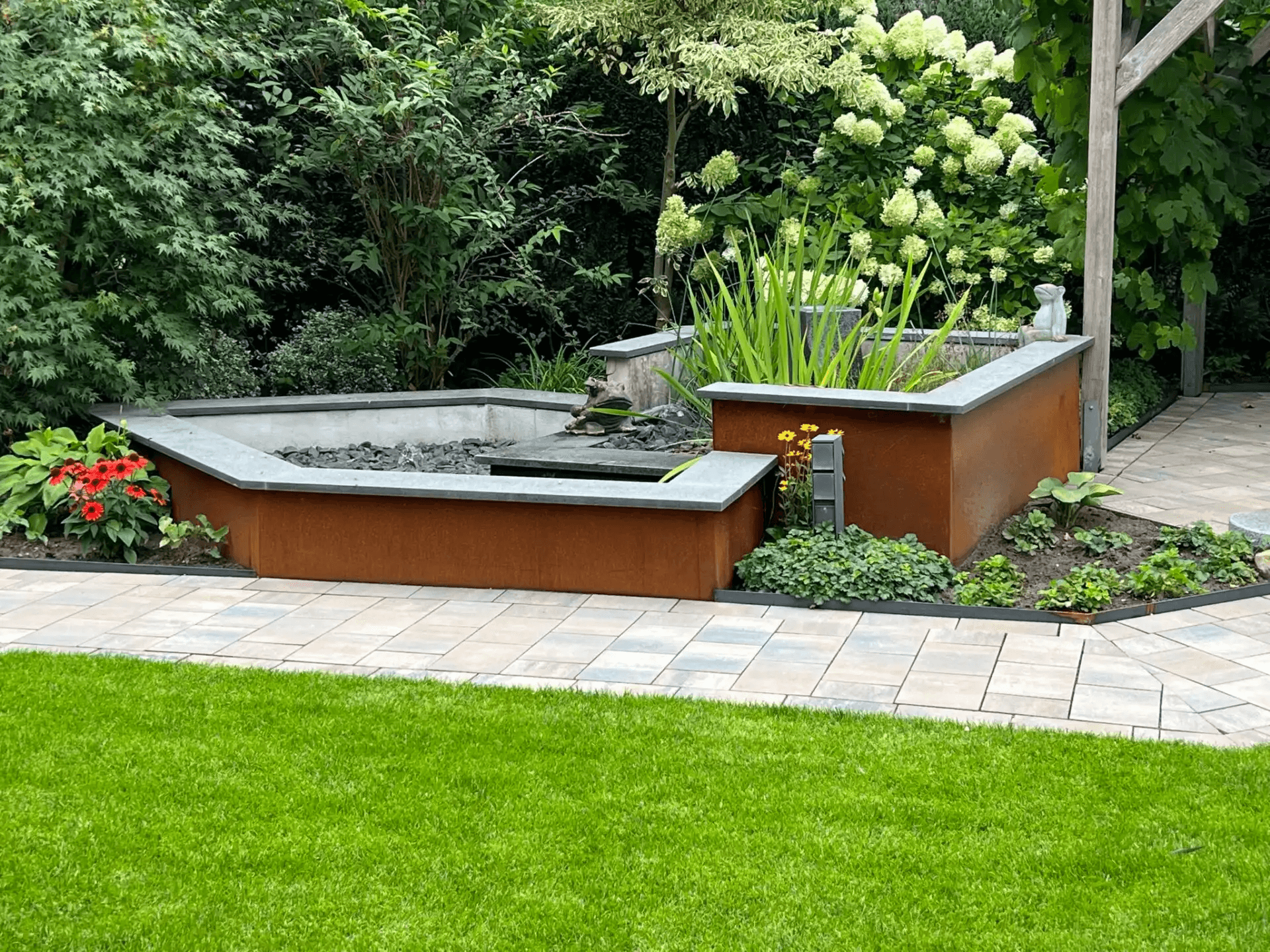 Brunnenverkleidung aus Cortenstahl mit Natursteinabdeckung in einem Garten in Delbrück-Lippling